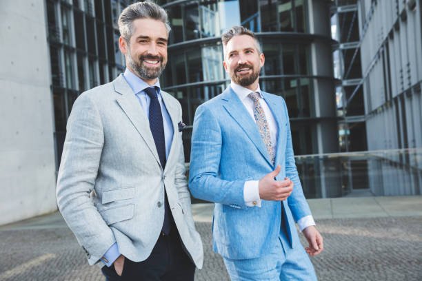 Two IT professionals standing side by side in front of Berlin's skyline and Melbourne's skyline